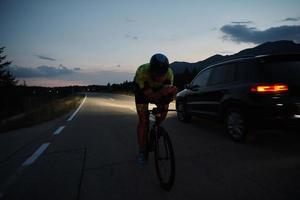 atleta de triatlón montando bicicleta por la noche foto