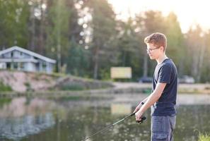 chico joven pescando en el lago con caña. concepto de estilo de vida de viaje vacaciones de verano. pesca pagada. foto