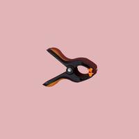 Plastic spring clamp isolated on pink background. Working hand tool. Black and orange spring clamp. Closeup. photo