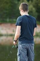 joven pescando en el lago con caña. concepto de estilo de vida de viaje vacaciones de verano. foto