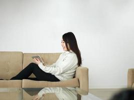 asian woman using Digital Tablet on sofa photo