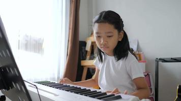 petite fille asiatique apprenant à jouer du piano de base en utilisant un clavier de synthétiseur électrique pour la musique instrumentale débutant auto-apprenant à la maison video