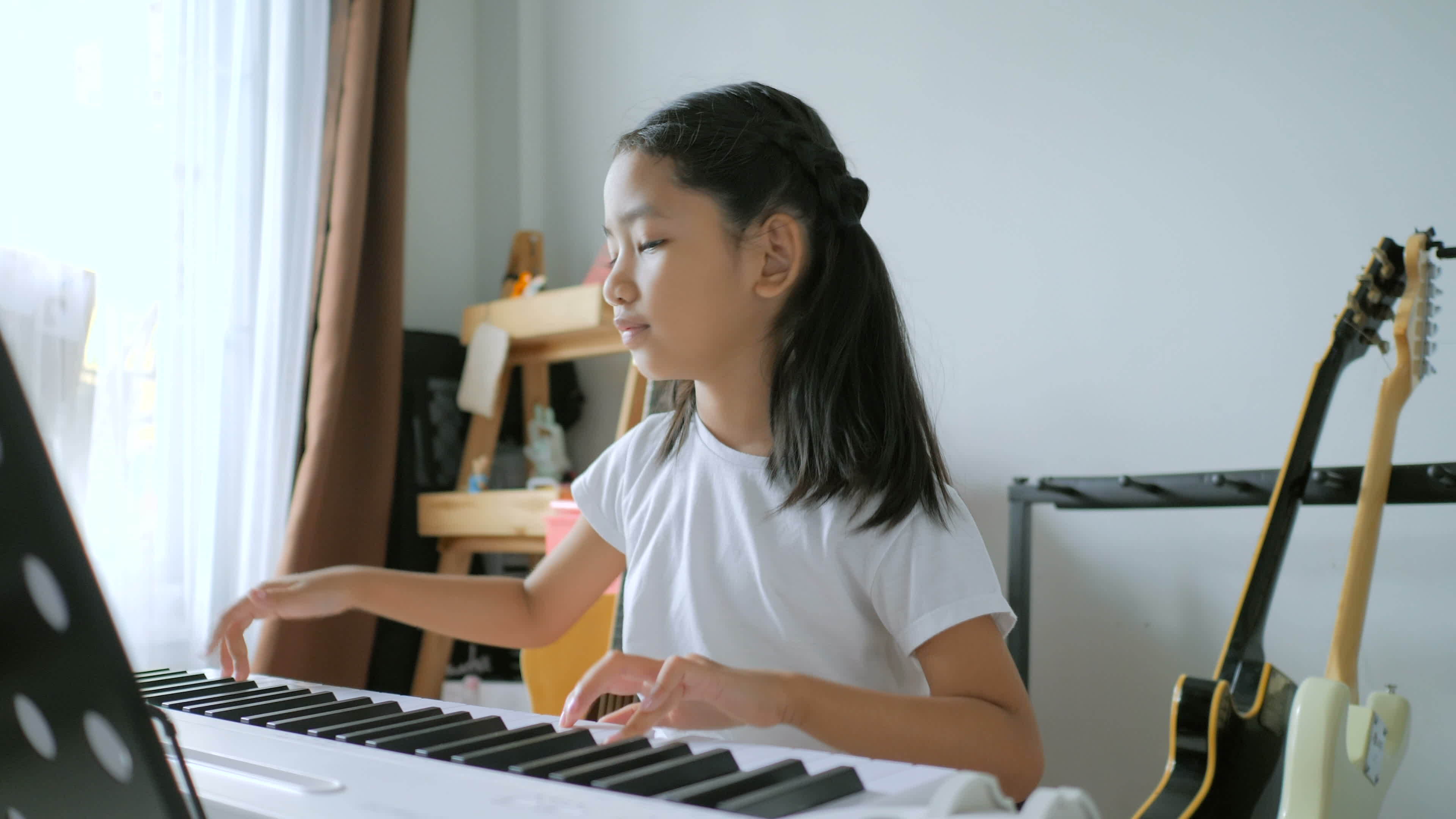 Linda garota asiática aprendendo música de piano online com