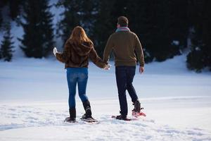 couple having fun and walking in snow shoes photo