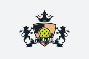 heraldic pickleball logo with a ball, ribbon, shield, lions, and crown.