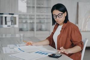 Accountant examining reports. Business assistant in glasses is working with data charts from home. photo