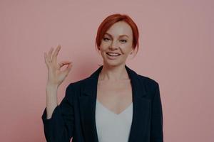 Headshot of young happy sitisfied business woman being sitisfied with choice, showing ok sign photo