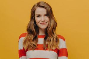 Kind friendly female feeling great and emitting positive vibes while posing in studio photo