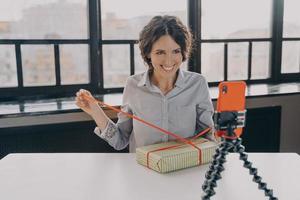 Positive italian woman blogger recording video blog about christmas gift at home photo