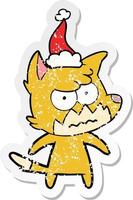 distressed sticker cartoon of a annoyed fox wearing santa hat vector