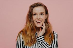 Happy young teenage girl demonstrating wow expression while posing over pink background photo