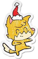 distressed sticker cartoon of a friendly fox wearing santa hat vector