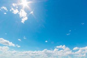 Natural abstract background of bright blue sky and fluffy white clouds on a sunny, light a flare and sun. photo