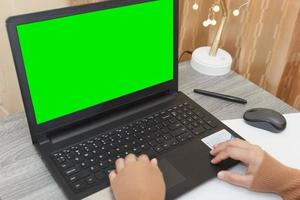 woman working online on laptop computer with green screen for content mockup. Concept of working from home during coronavirus outbreak. photo