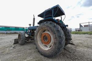 tractor azul estacionado en un claro en preparación para la capa superior del suelo y un hermoso cielo azul en el fondo. el concepto de una excavadora prepara la capa superior del suelo para la construcción. foto