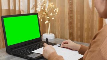 mujer que trabaja en línea en una computadora portátil con pantalla verde para la maqueta de contenido. concepto de trabajar desde casa durante el brote de coronavirus. foto