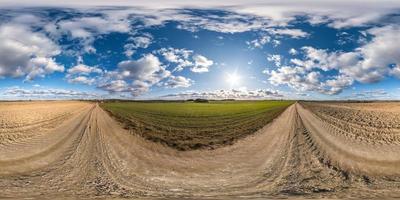 panorama hdri esférico completo sin costuras vista en ángulo de 360 grados en camino de grava entre campos en primavera con impresionantes nubes en proyección equirectangular, listo para contenido de realidad virtual vr ar foto