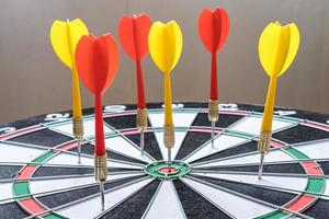 Red and yellow dart arrows hitting in the target center of dartboard. Success hitting target aim goal achievement concept photo