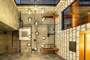 looking up on gray concrete ceiling with halogen spots and edison lamps in loft office room with air conditioning and orange ventilation pipe photo