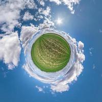 Little planet transformation of spherical panorama 360 degrees. Spherical abstract aerial view in field with awesome beautiful clouds. Curvature of space. photo