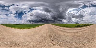 vista de ángulo de 360 grados de panorama hdri esférico completo sin tráfico en camino de grava sin tráfico entre campos con cielo nublado antes de tormenta en proyección equirectangular, listo para contenido de realidad virtual vr ar foto