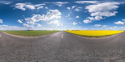 Panorama esférico completo sin costuras Vista angular de 360 grados en carretera asfaltada sin tráfico entre campos de colza con cielo nublado en proyección equirectangular, contenido vr ar foto