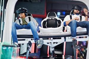 Two young indian people having fun with a new technology of a vr headset at virtual reality simulator. photo