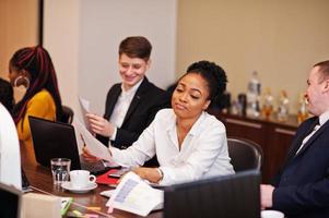 Multiracial business team addressing meeting around boardroom table. photo