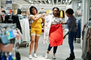 Three african woman choosing clothes at store. Shopping day. photo