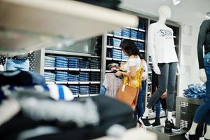 Three african woman choosing clothes at store. Shopping day. They buying jeans. photo