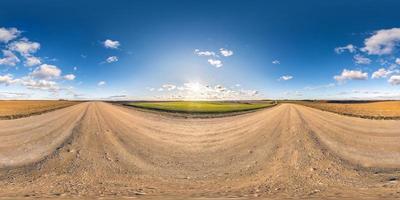 Full spherical seamless panorama 360 degrees angle view on no traffic gravel road among fields in evening  before sunset with clear sky in equirectangular projection, VR AR content photo