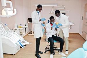 tres colegas médicos afroamericanos en clínica dental con una manzana. foto