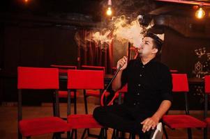 Asian man smoke hookah and having rest at lounge bar. photo