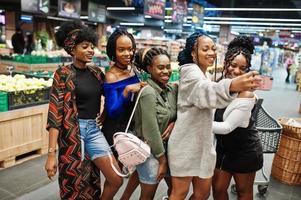 grupo de cinco mujeres africanas haciendo selfie por teléfono en el supermercado. foto