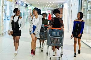 Group of african womans walking with shopping carts on mall. photo