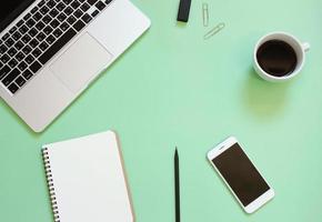 Creative flat lay design of workspace desk with laptop, blank notebook, smartphone, coffee, stationery with copy space background photo