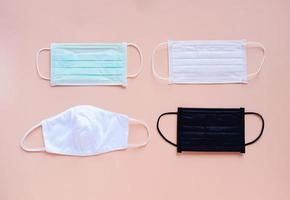 Flat lay of various kind and color of hygienic masks on bright pastel peach orange color background, health care and prevent the spread of pandemic Covid-19 and Coronavirus, photo