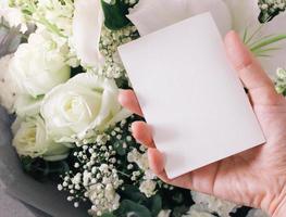 mano que sostiene la tarjeta en blanco en el ramo de flores, el día de san valentín y el concepto de amor foto