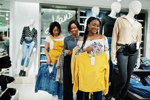 Three african woman posed near mannequins in clothes store. Shopping day at jeans sector. photo