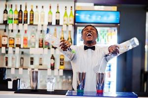 camarero afroamericano trabajando detrás del bar de cócteles. preparación de bebidas alcohólicas. foto