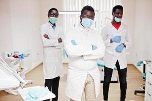 tres médicos varones afroamericanos con los brazos cruzados en la clínica dental. foto