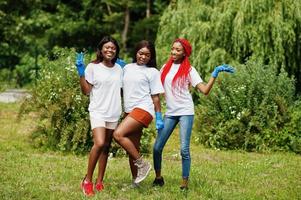 Three african volunteer womans in park. Africa volunteering, charity, people and ecology concept. photo