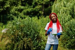 African red haired volunteer woman with clipboard in park. Africa volunteering, charity, people and ecology concept. photo