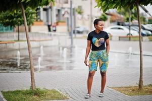 Young african american woman posed against fountain with telephone at hand. photo