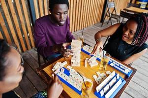 Group of three african american friends play table games. photo