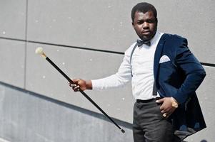 apuesto hombre afroamericano de moda con ropa formal y pajarita con bastón. foto