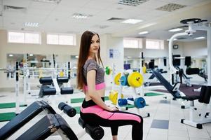 Young brunette sexy slim girl doing workout at gym. photo