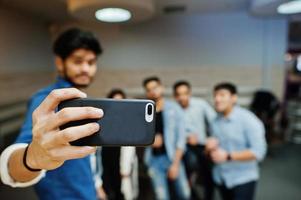 Close up hand of asian man holding mobile phone and making selfie with friends. photo