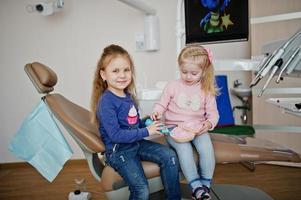 Two cutie little baby girls at dentist chair. Children dental. photo