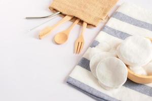 Flat lay of sustainable products, wooden spoon, stainless straw and natural cotton on white background and copy space, eco friendly and zero waste concept photo